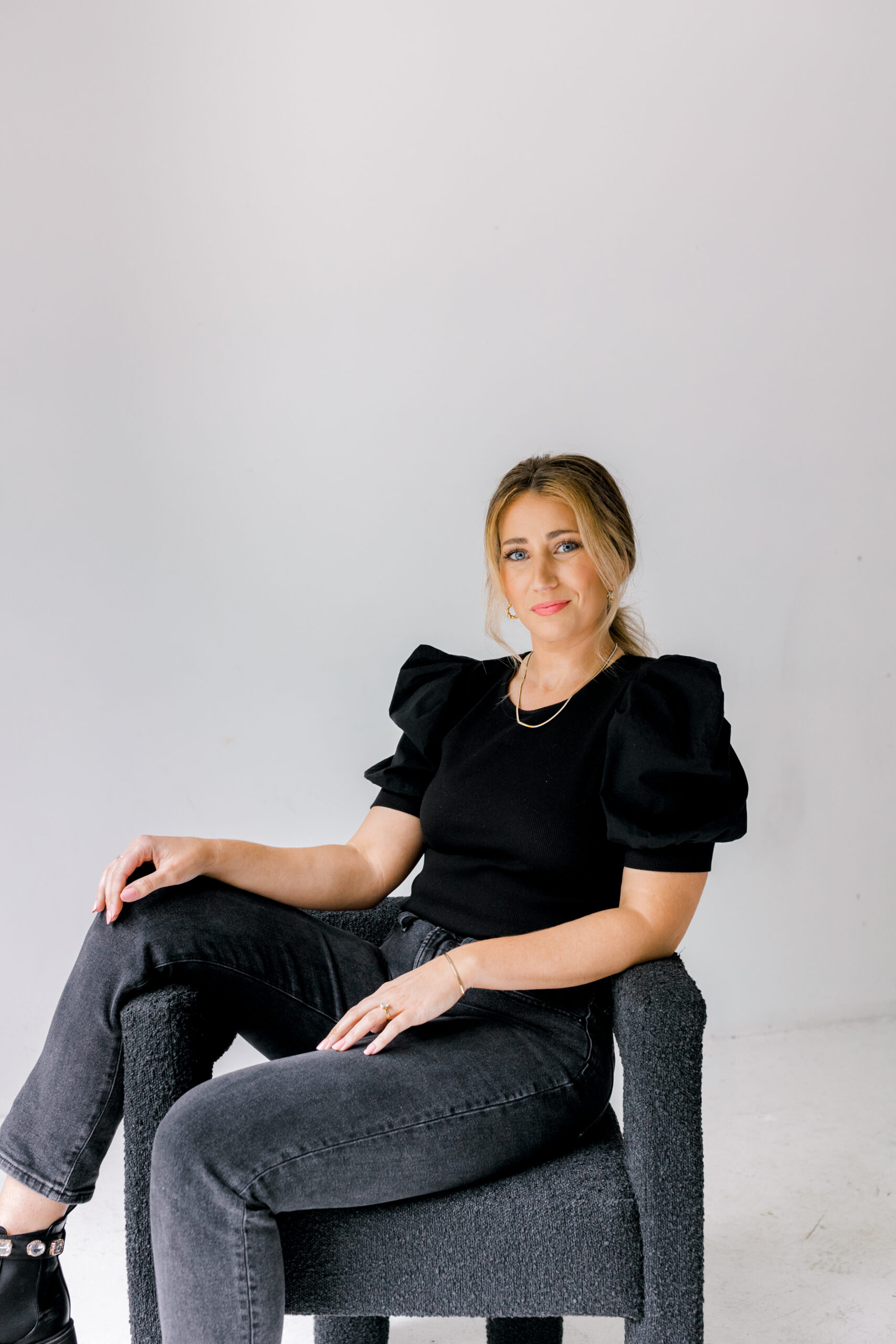 Woman sitting on black chair in photography studio